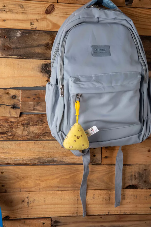 Plush cheese keychain on a blue backpack