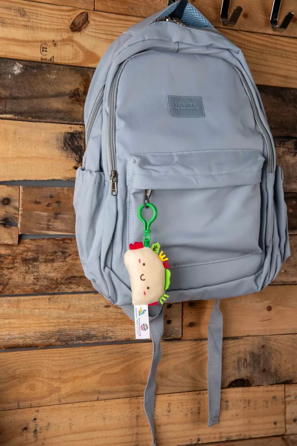 Plush taco keychain on a blue backpack